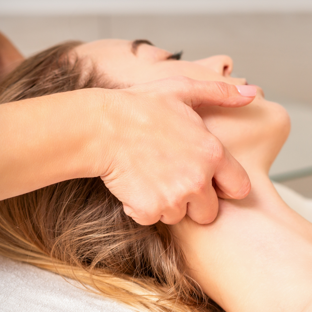 Therapist gently cradling a relaxed guest's neck during a lymphatic drainage massage at PURE