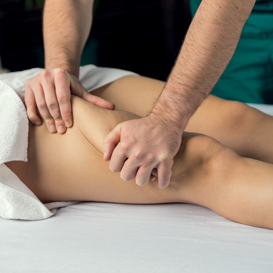 Therapist's hands working along the back of a guest's leg during a lymphatic drainage massage at PURE