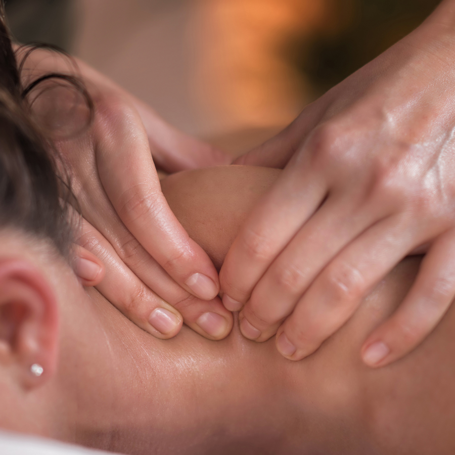 Therapist working into the neck and shoulders of a guest during a sports massage at PURE