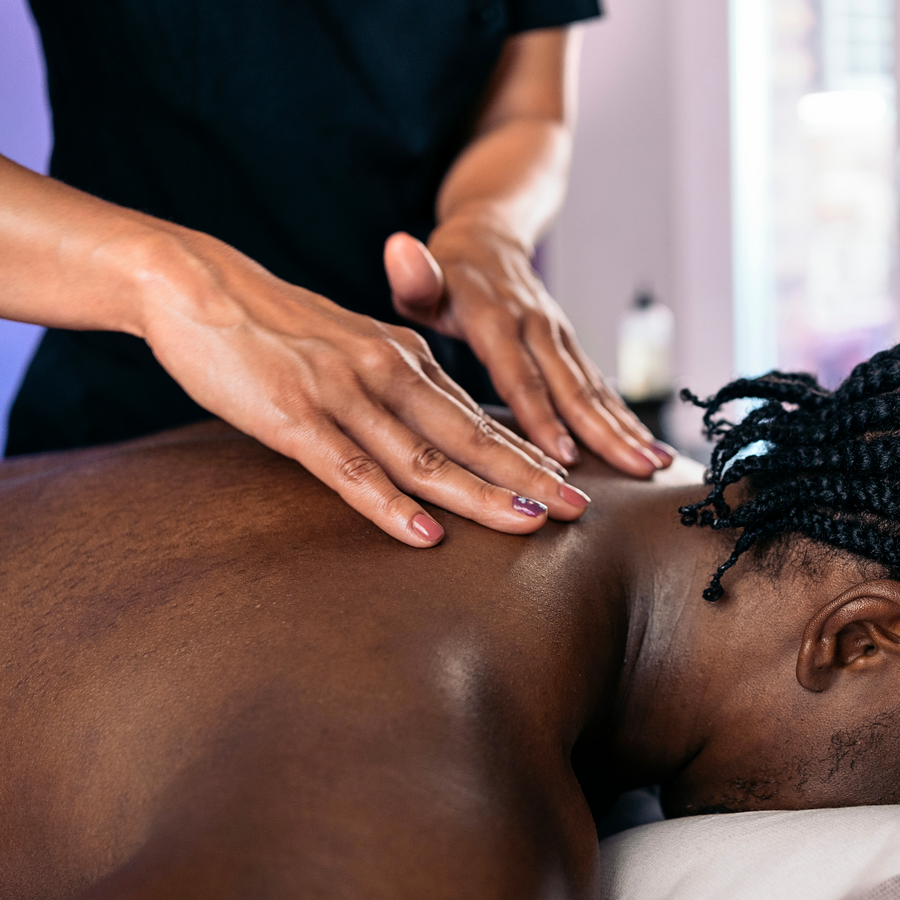 Therapist's hands massaging a guest's upper back and shoulders during a sports massage at PURE